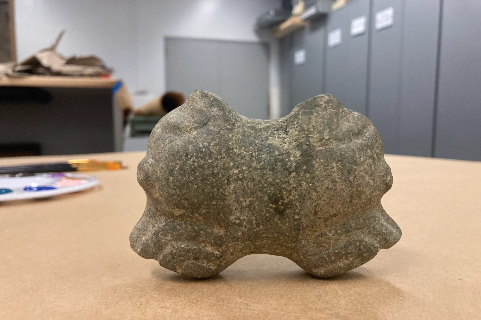 The stone macehead on a table, carved as a double-headed dog with heads facing opposite ways.