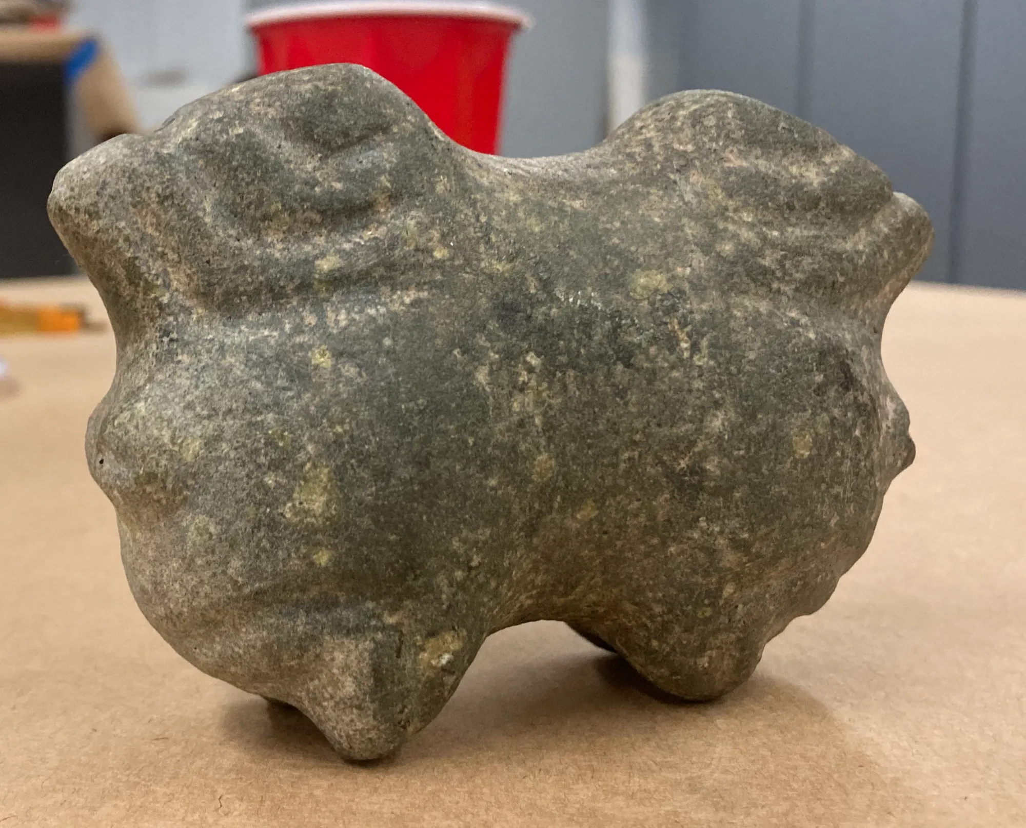 The stone macehead turned upside down on a table, where its shape becomes a crouching horned frog.